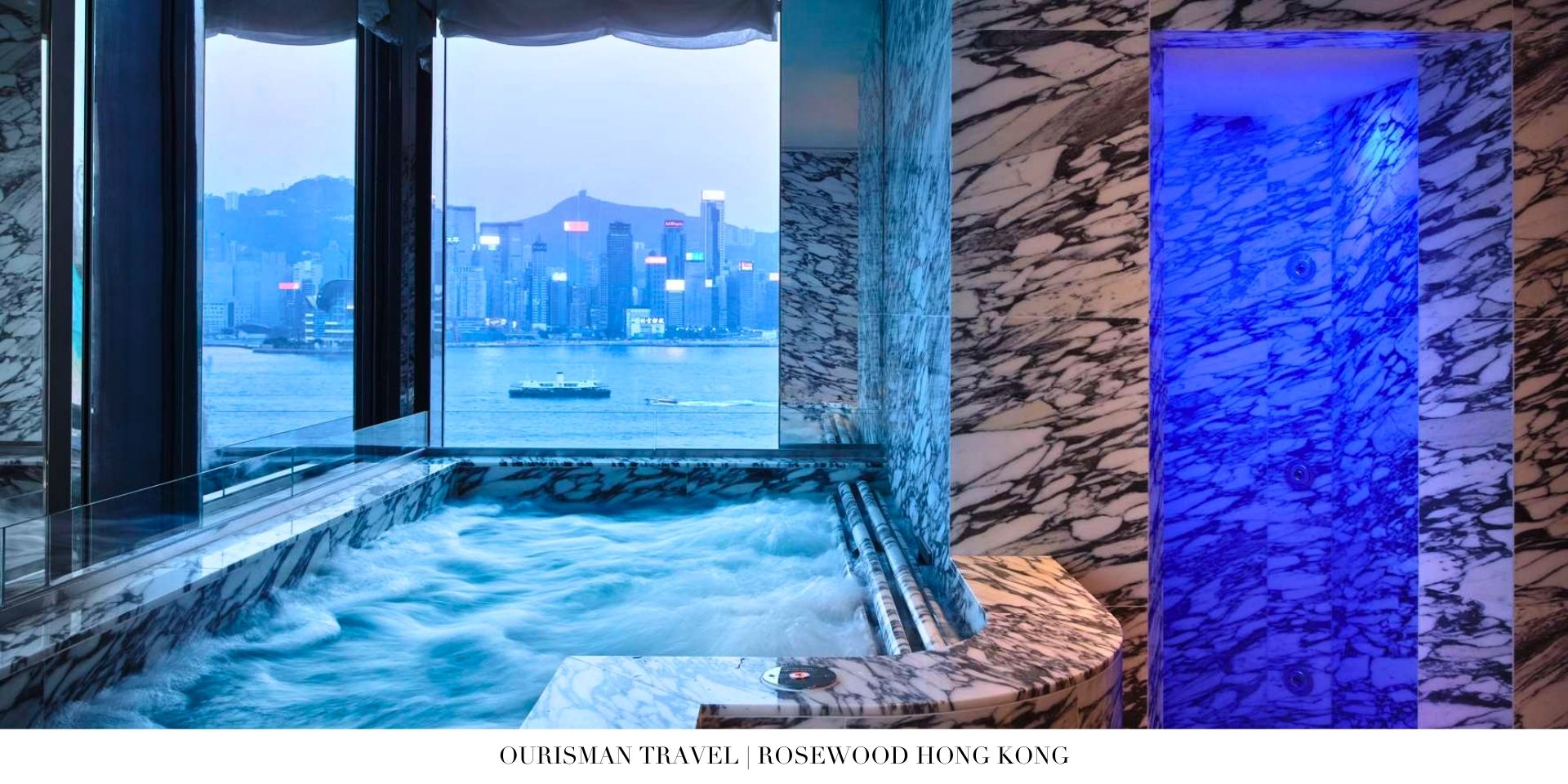 Evening view of Rosewood Hong Kong lit up against Victoria Harbour and city lights