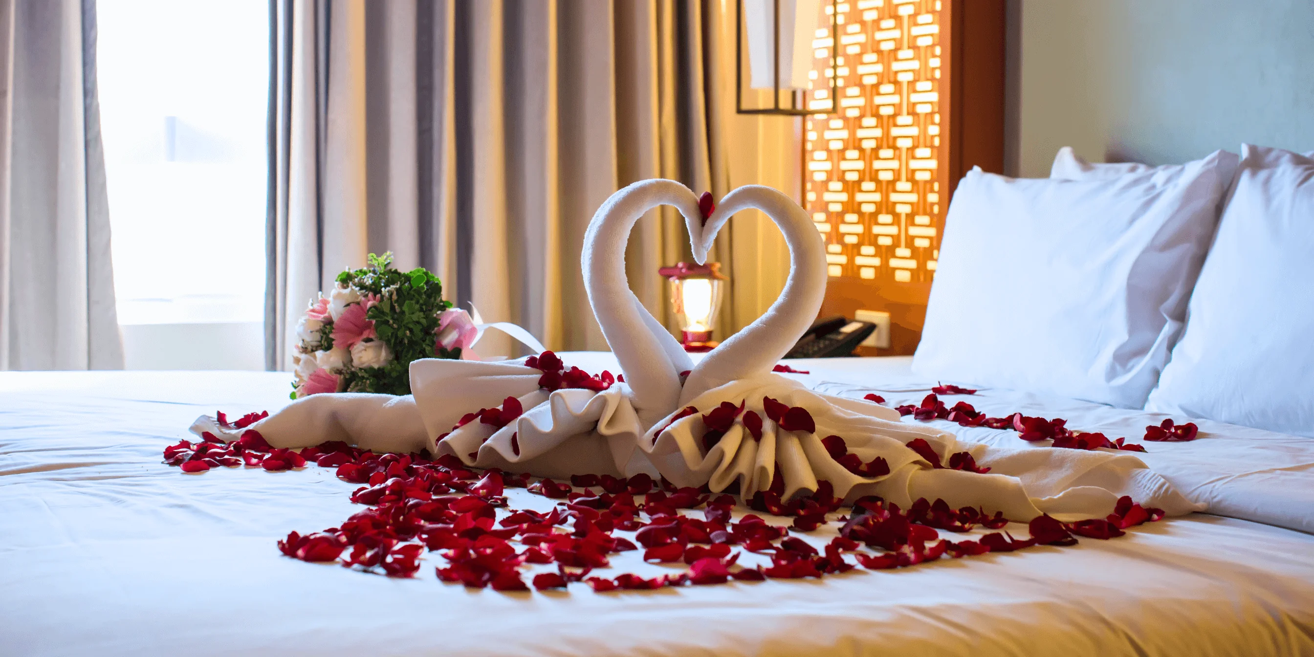 Romantic hotel bed with rose petals and towel swans