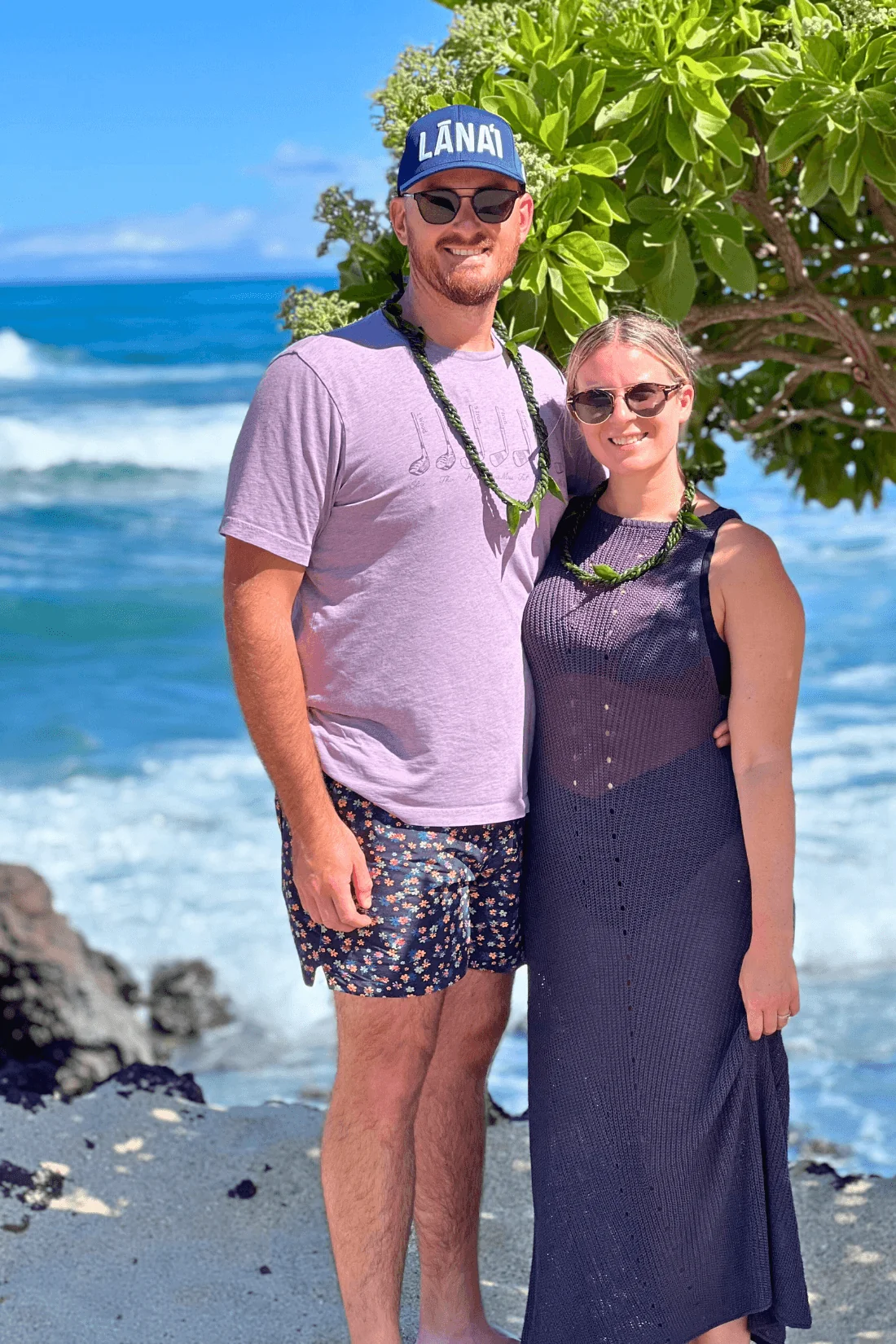 Couple standing by ocean in Hawaii wearing leis