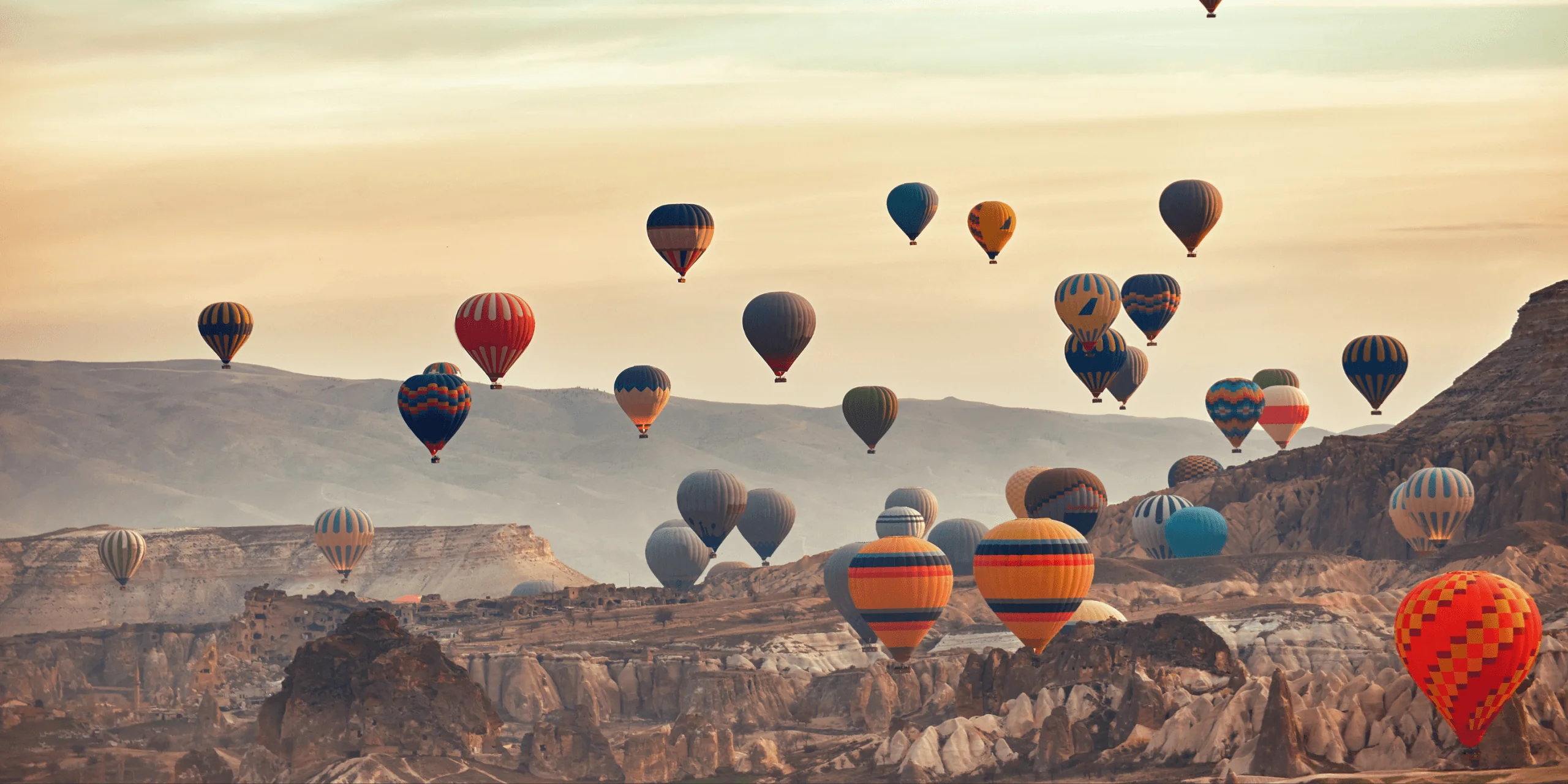 Hot air balloons over valley at sunrise