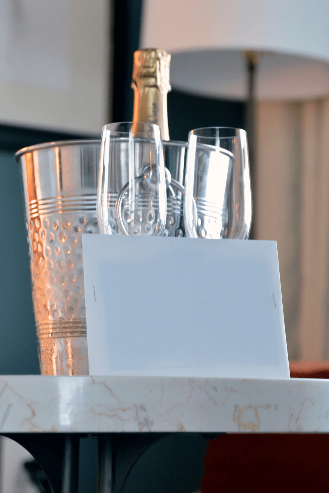 Champagne bottle with glasses and welcome note on table