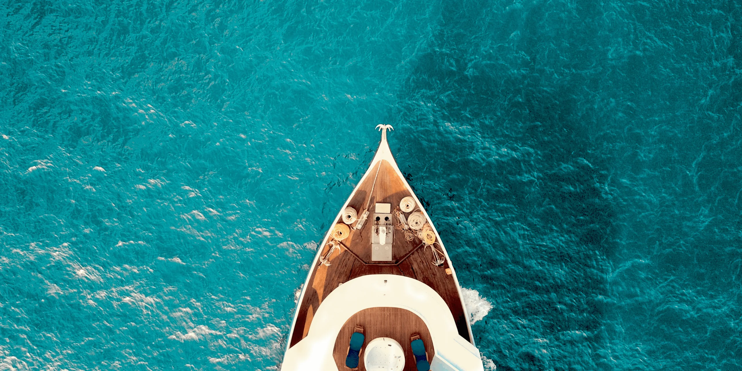 Boat sailing in clear blue ocean from above