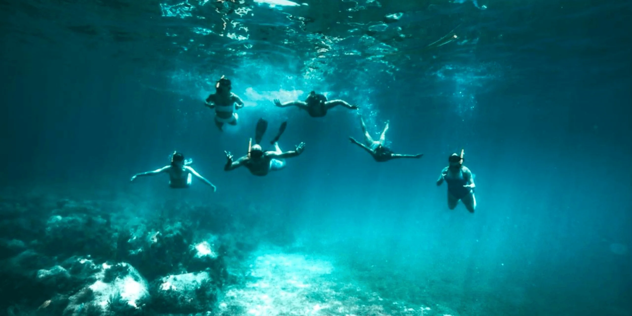 Snorkeling in clear blue ocean with group underwater