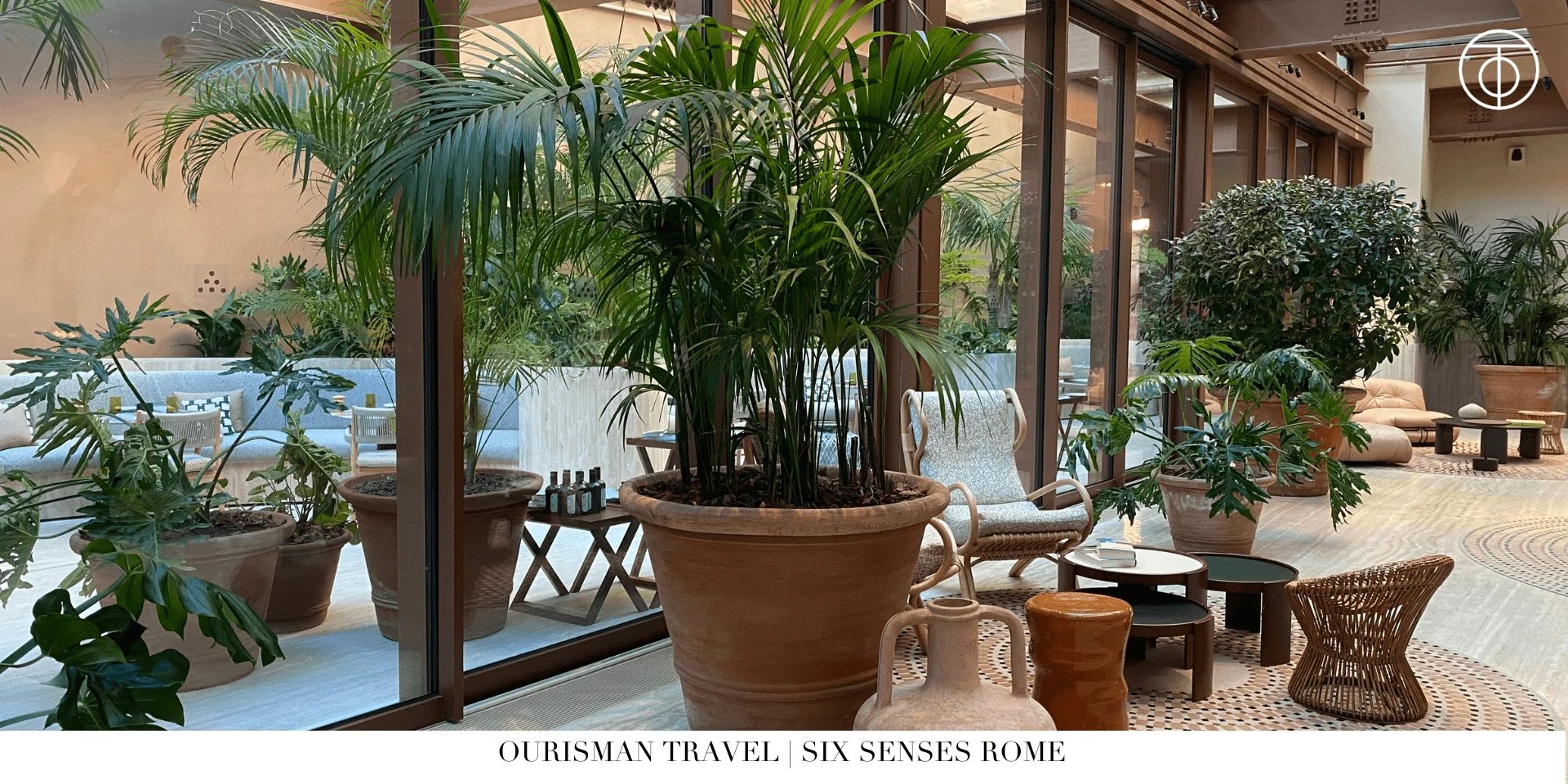 Sun-filled atrium at Six Senses Rome with indoor palm trees and modern seating