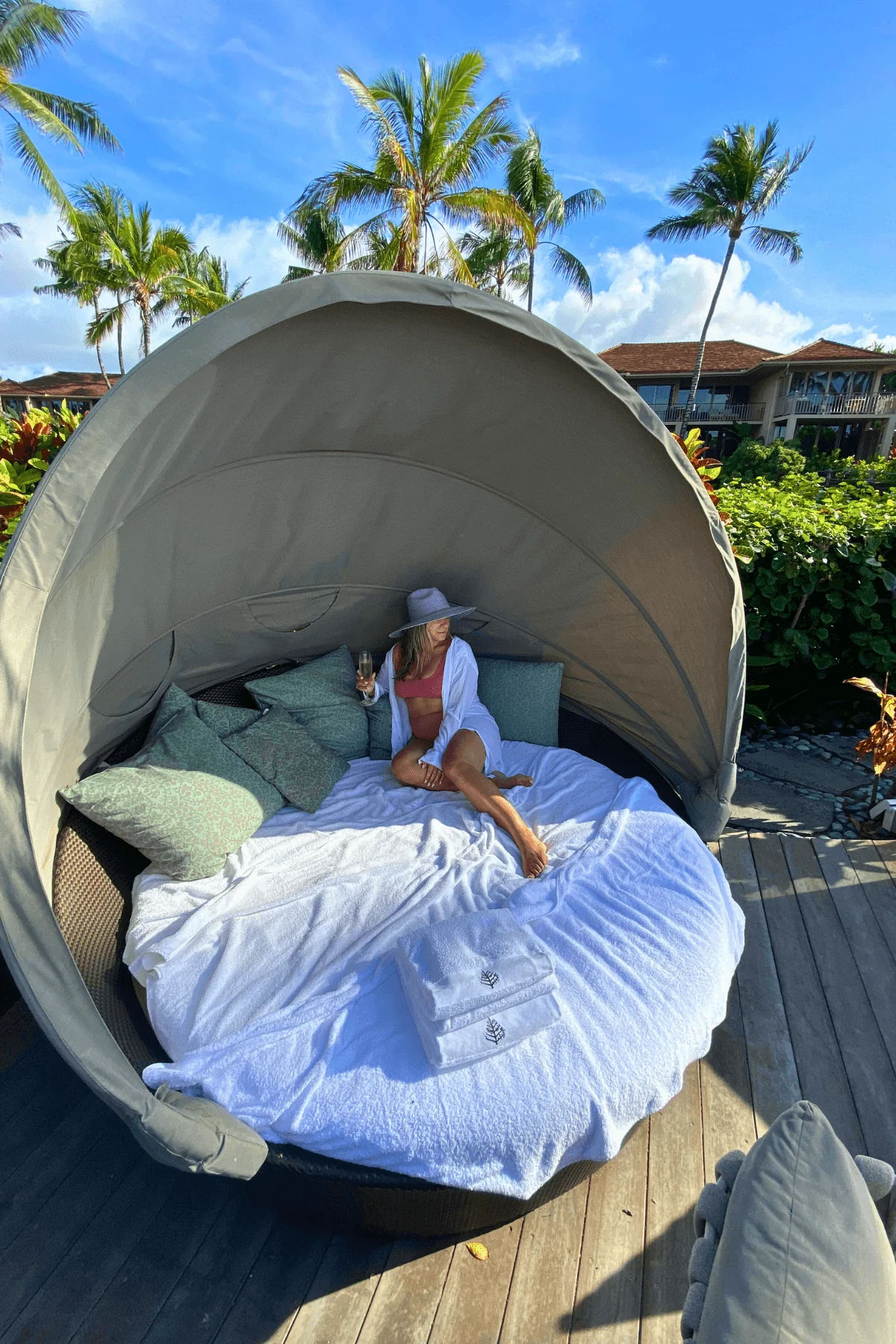 Woman relaxing on outdoor daybed with palm trees at beach resort