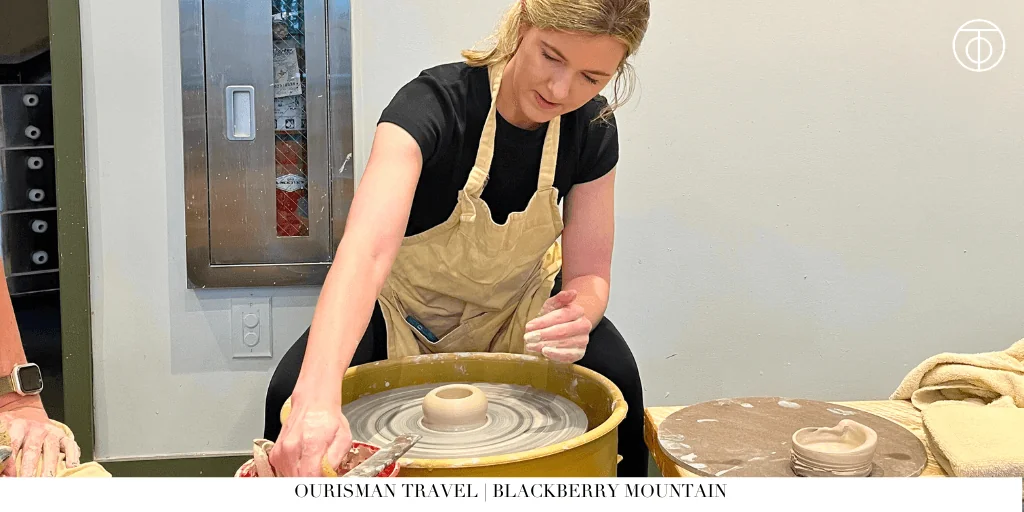 Guest shaping pottery on a wheel during a workshop at Blackberry Mountain