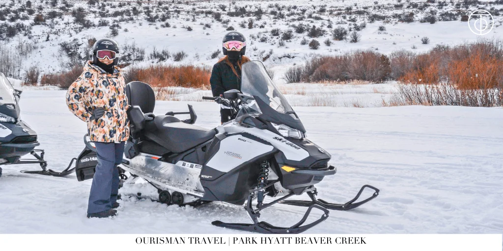 Traveler riding a snowmobile across a snowy landscape near a mountain resort