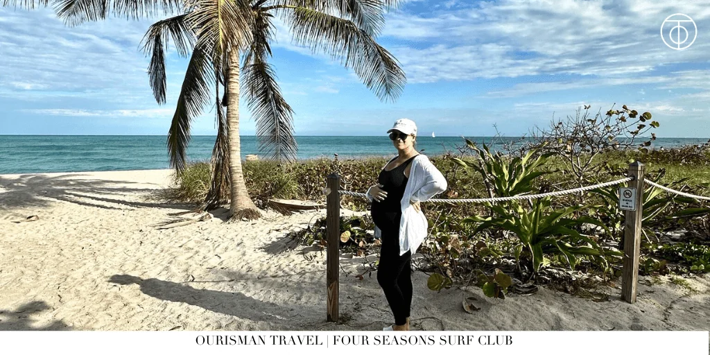 Woman standing on a sandy beach with palm trees at Four Seasons Hotel at The Surf Club in Surfside Miami