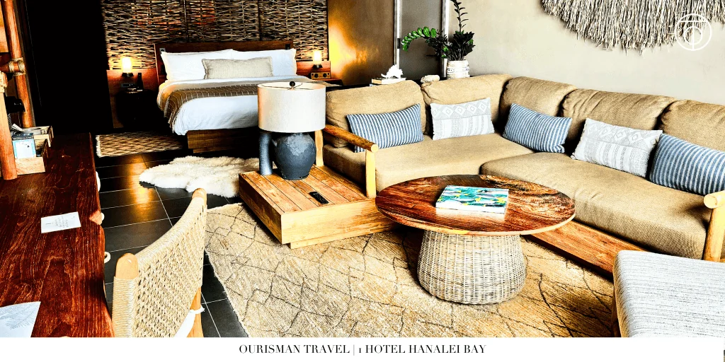 Suite living area at 1 Hotel Hanalei Bay in Kauai with sofa, wood table, and bedroom in background