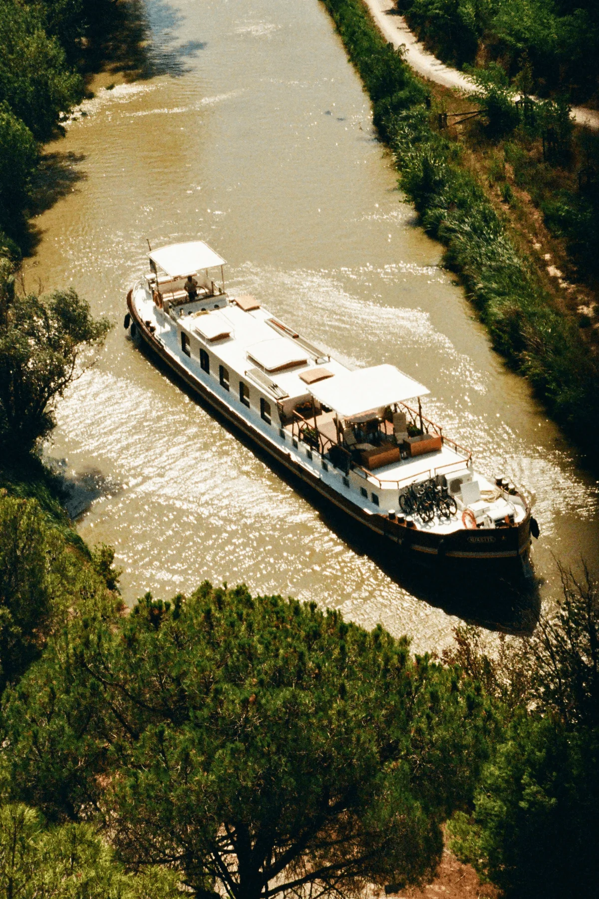 Luxury river cruise ship sailing along a narrow canal surrounded by greenery in Europe