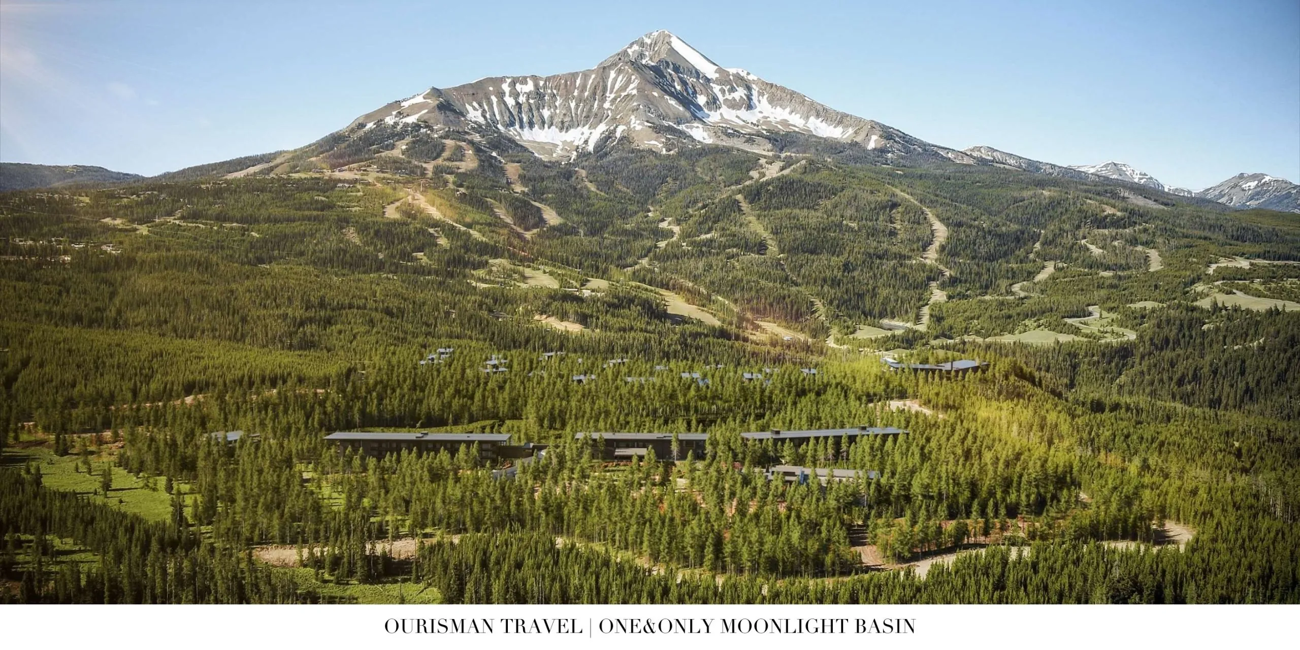 Aerial view of One&Only Moonlight Basin surrounded by forested hills and snow-capped peaks in Big Sky.