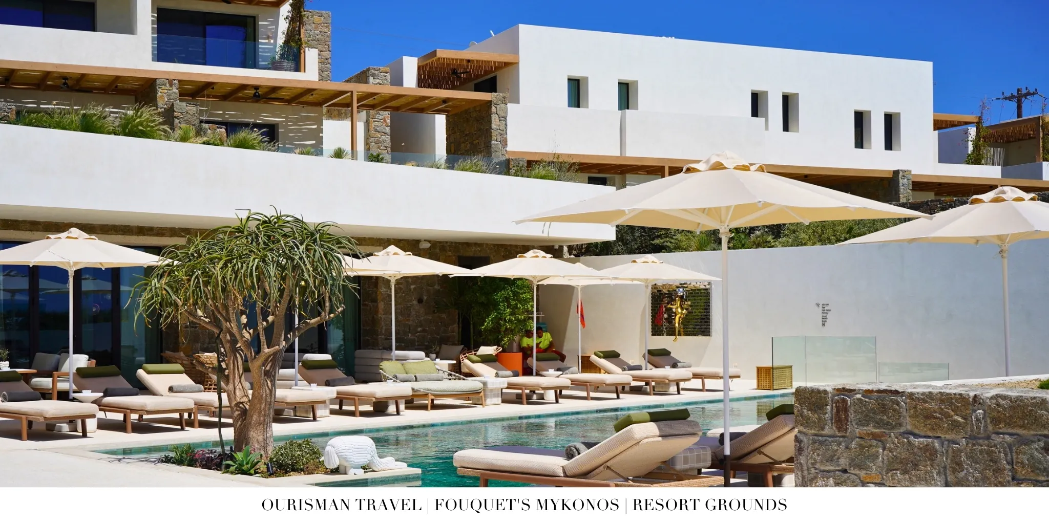 Fouquet’s Mykonos main pool with sunbeds and white hotel buildings