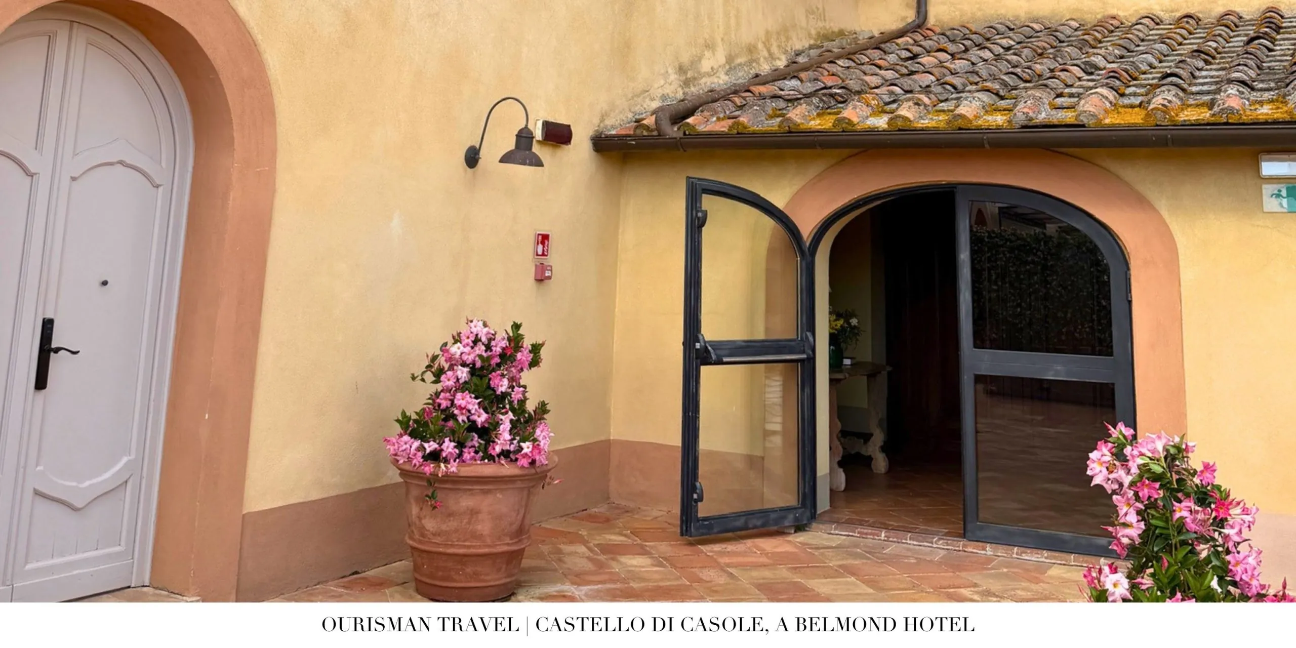Historic entrance to Castello di Casole, a Belmond Hotel, with traditional Tuscan architecture and floral displays.