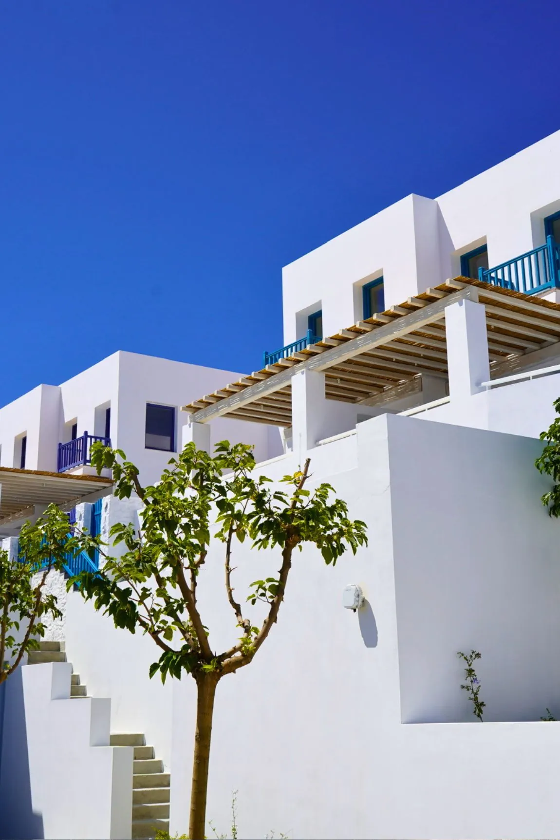 Whitewashed guest room buildings and landscaped walkway at Four Seasons Mykonos